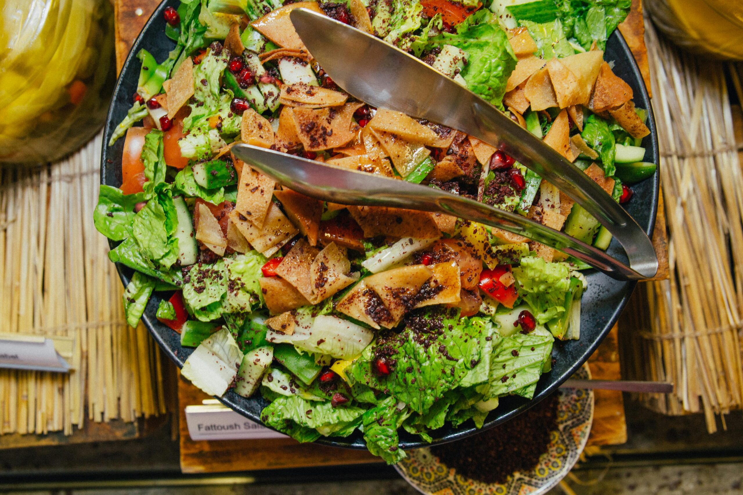 A vibrant Fattoush salad showcasing fresh vegetables, pita chips, and pomegranate seeds in a black bowl.