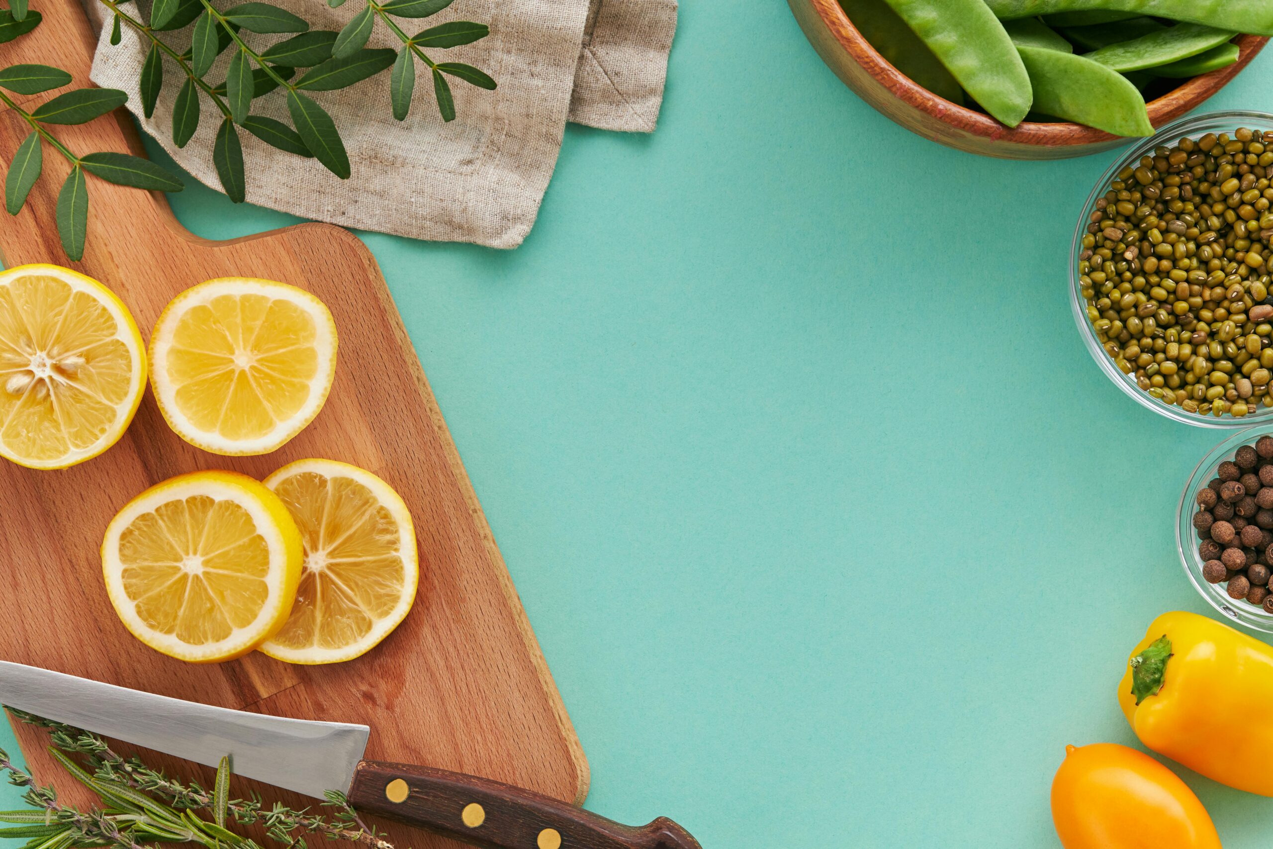 A bright flat lay of citrus fruits, vegetables, and spices on a teal background, perfect for culinary themes.